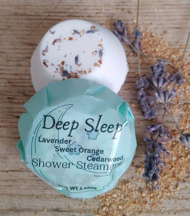 Round white shower steamer with dried lavender and a teal label wrap on wood
