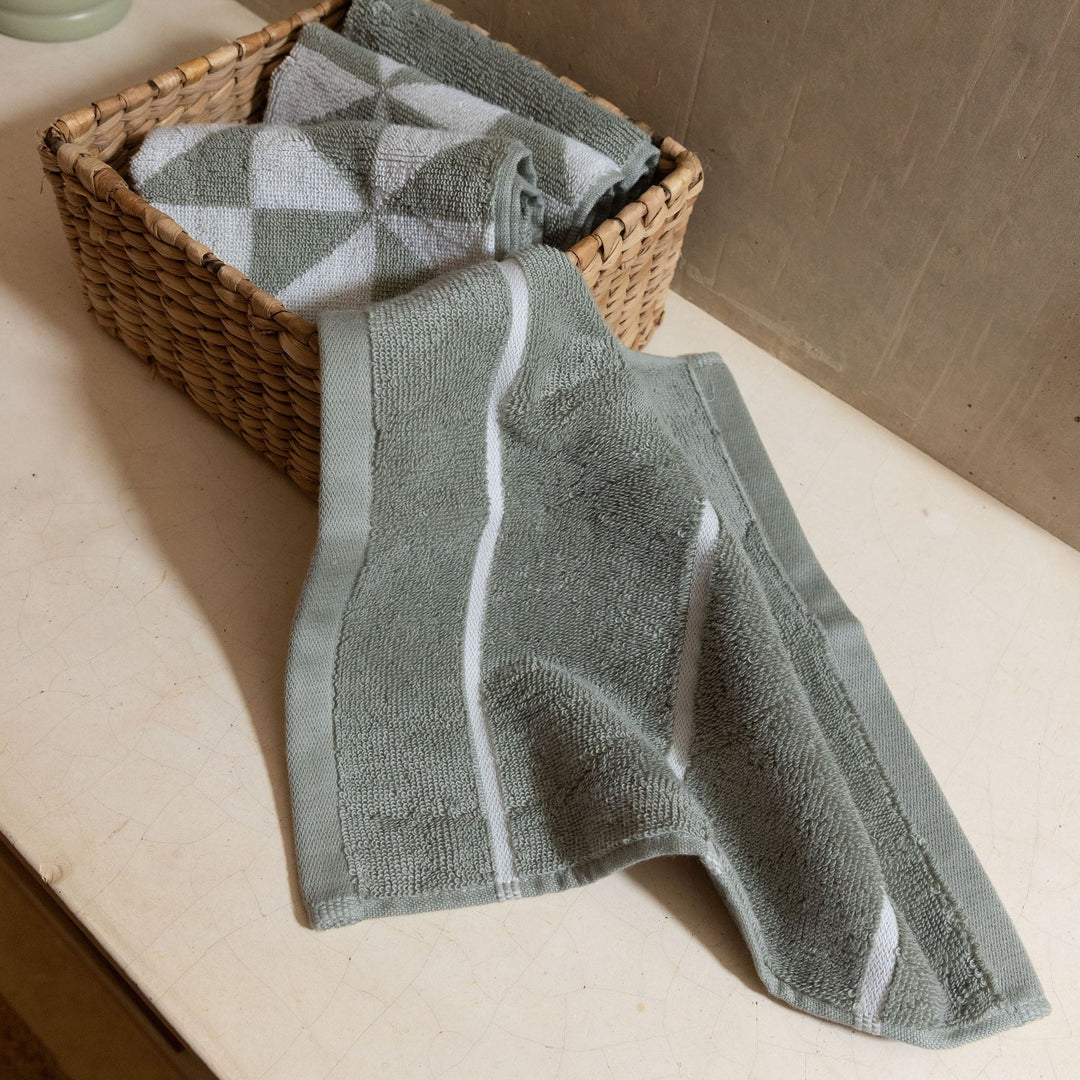 Folded sage green and ecru cotton towels with white geometric stripe bands