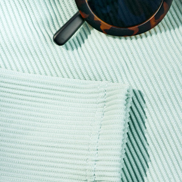 Mint ribbed swimsuit fabric close-up with visible seams