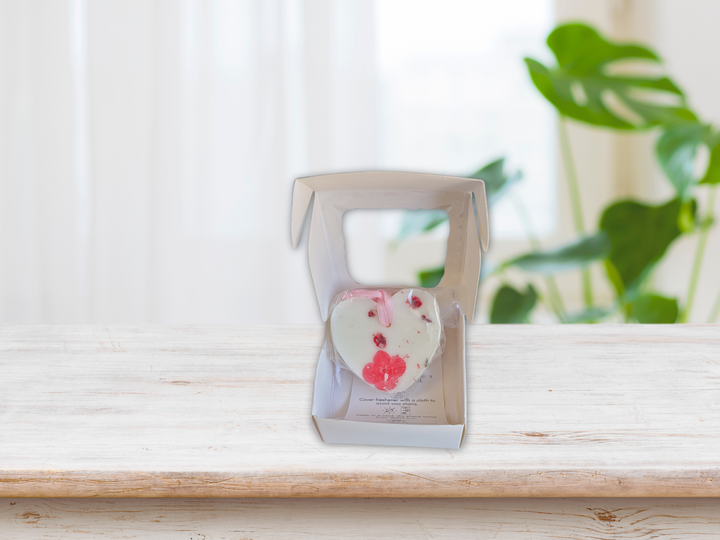 Heart-shaped floral wax sachet in an open box with pink and white dried petals