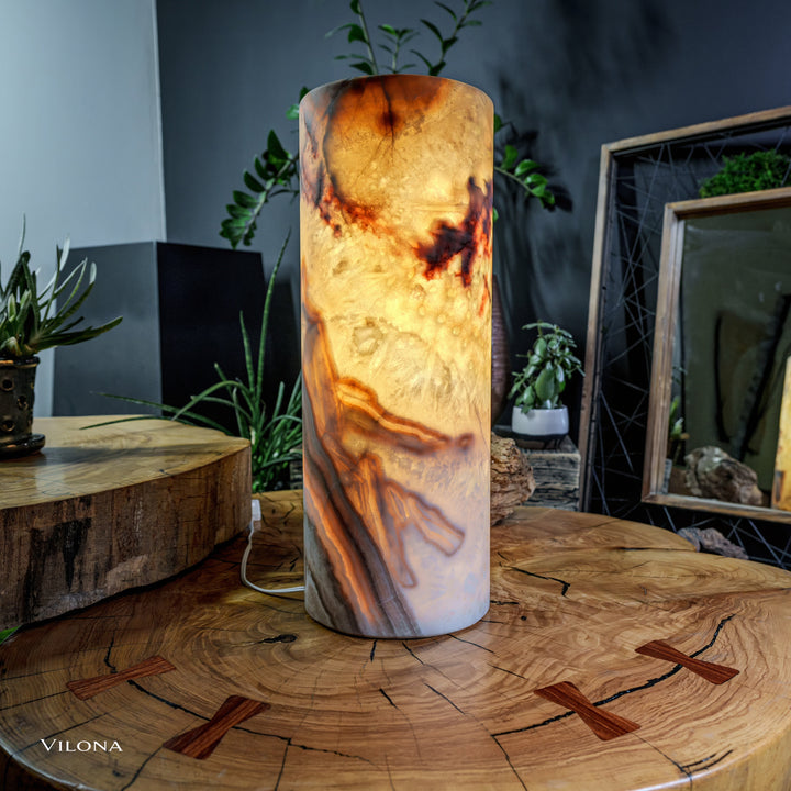 Onyx table lamp with cylindrical shade, amber and dark veining, lit glow