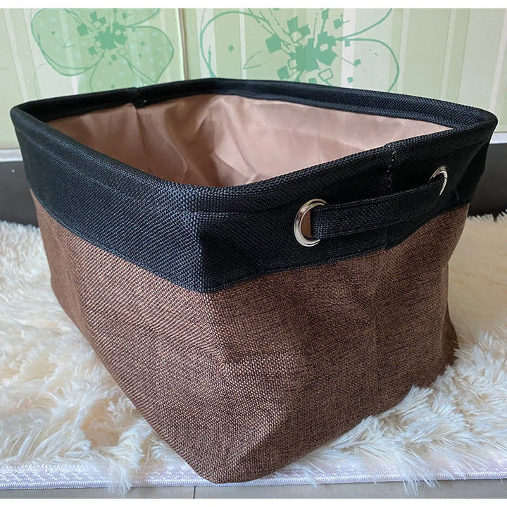 Dark blue and brown linen storage bin with black trim and reinforced side handles