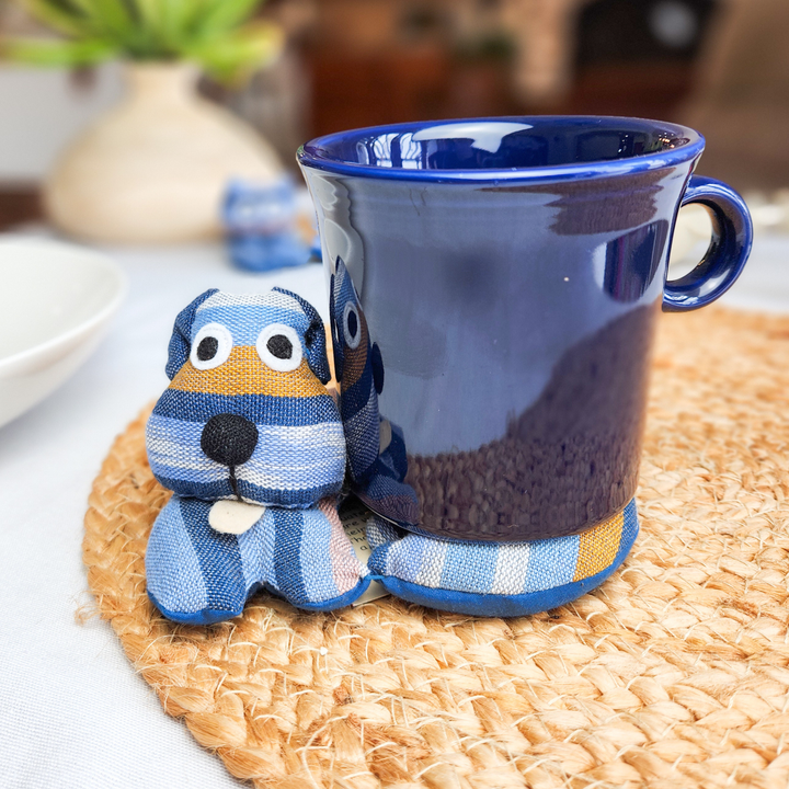 Round woven trivet with blue striped dog figurine beside a blue ceramic mug