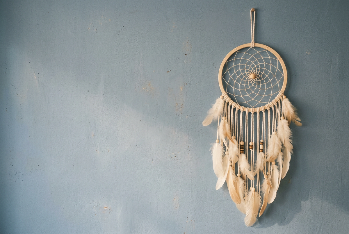 Dreamcatcher in natural cream and wood tones against a soft faded-blue background