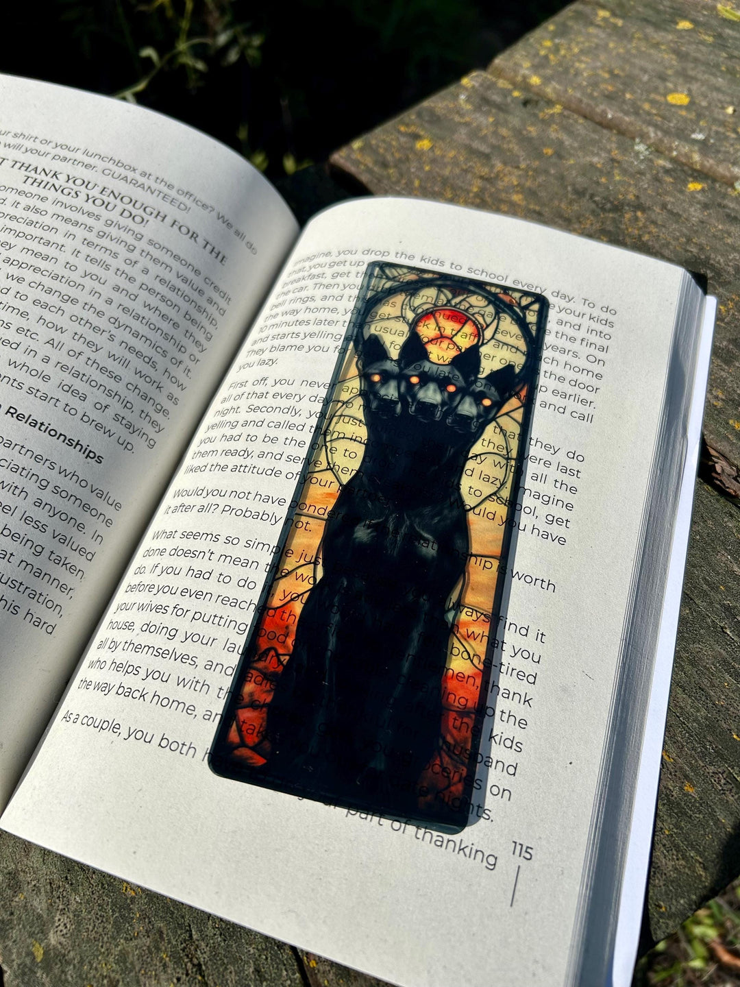 Fantasy bookmark showing black three-headed dog face with blue halo on open book page