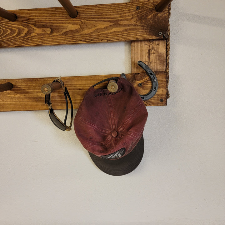 Hanging hat organizer rail with burgundy cap secured by dark U-shaped metal hook