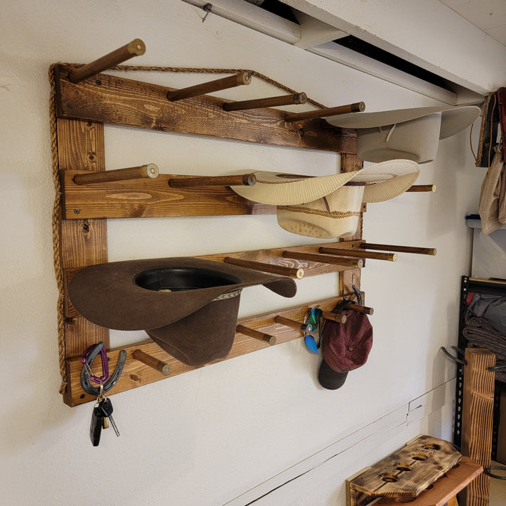 Wood wall hat organizer with tan hats on pegs, plus hooks and hanging brim holders