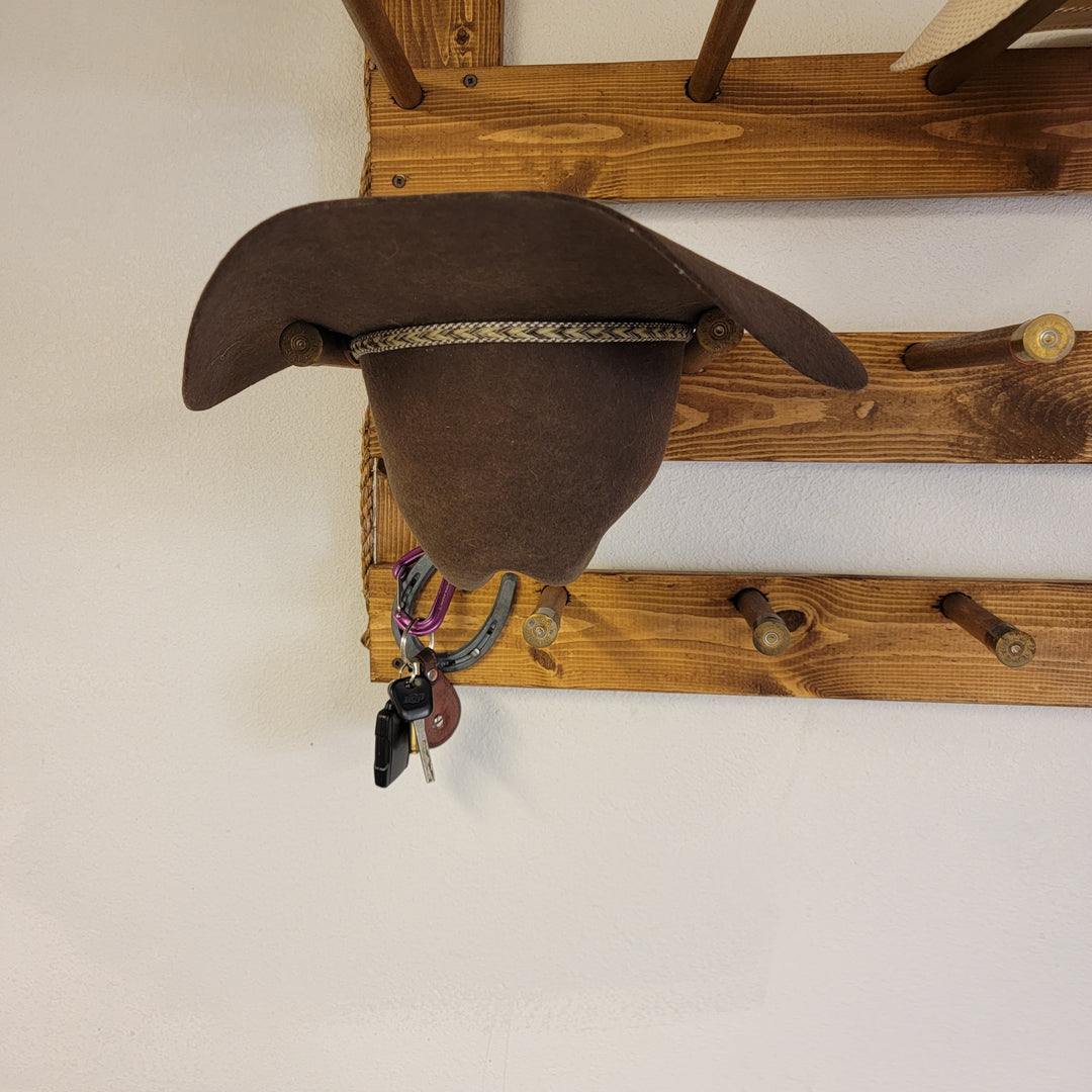 Wall-hanging wooden hat organizer with dark felt hat on upper peg bar