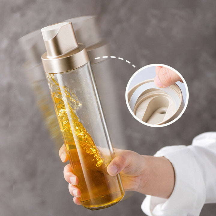 Clear glass oil dispenser bottle with open cap and gravity-flow nozzle