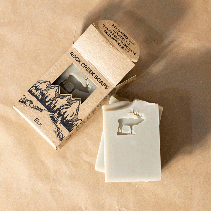 Lavender and sage soap bars with elk logo relief beside a label box