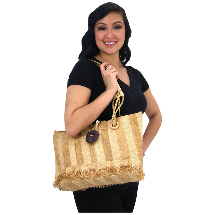Raffia tote bag with braided handles and dark button front, worn on model