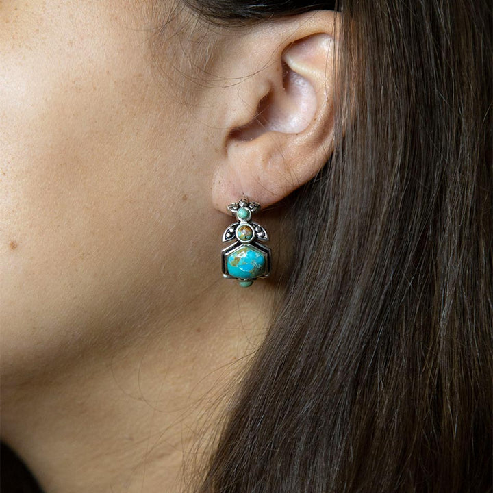 Turquoise and green gemstone hoop earrings with ornate silver setting, worn on ear