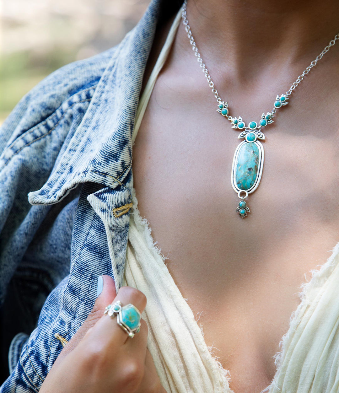 Sterling silver pendant necklace worn with oval blue turquoise centerpiece and round turquoise beads