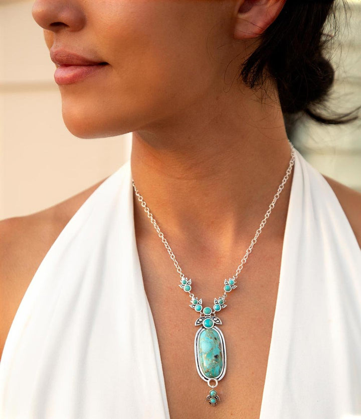 Sterling silver turquoise pendant necklace worn on neckline with oval blue turquoise centerpiece