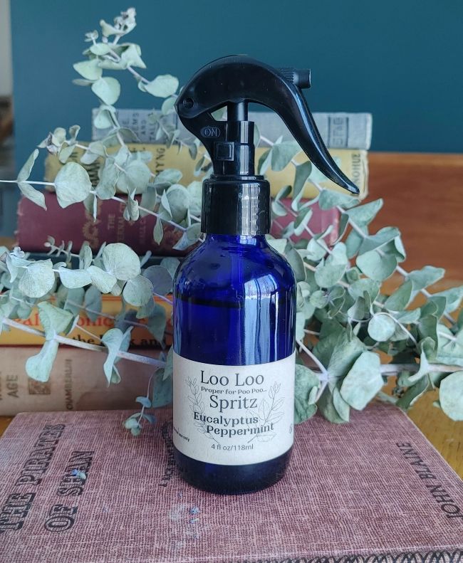 Deodorizing bathroom spray bottle in blue glass with black trigger, Eucalyptus Peppermint label.