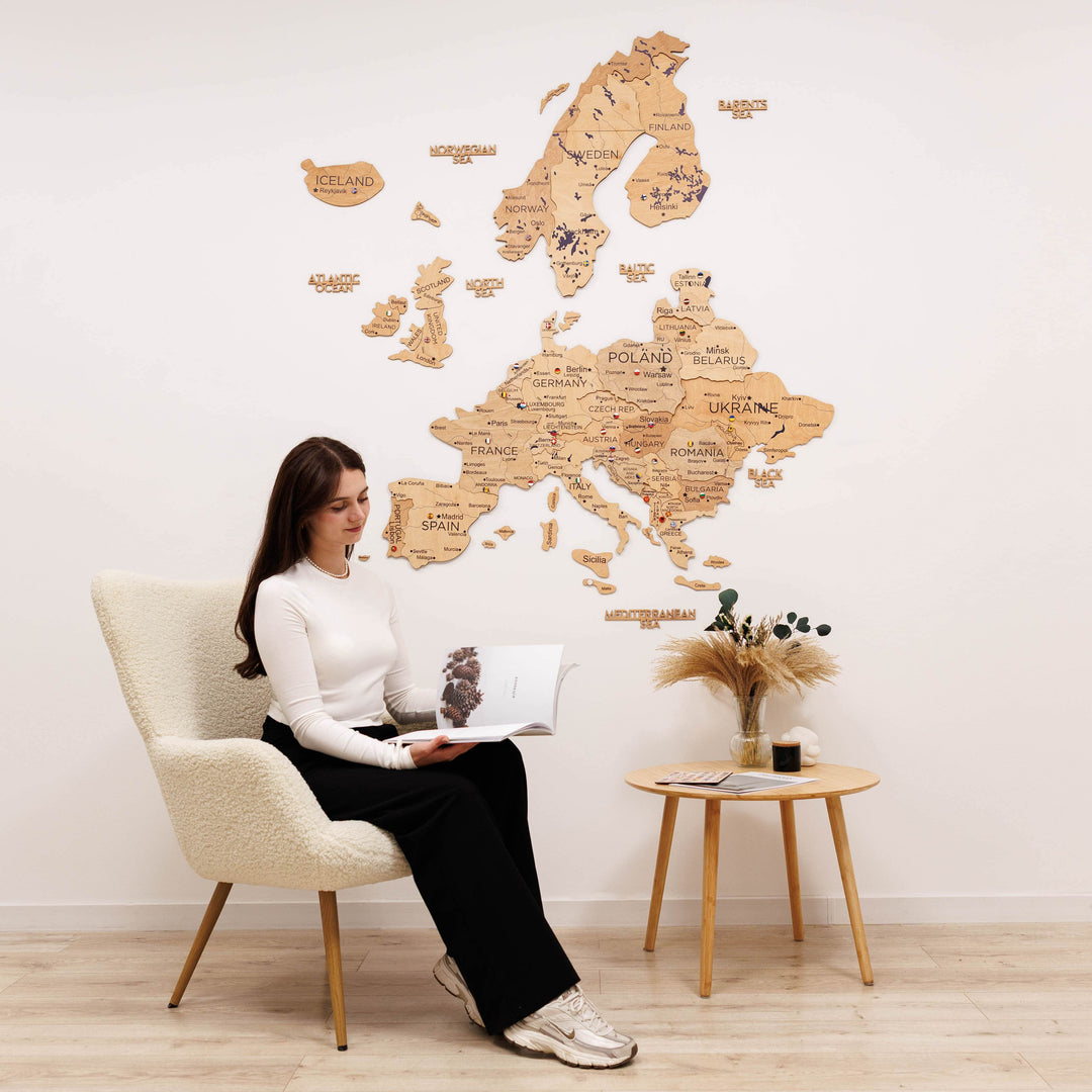 Gold Europe wooden wall map with country labels; seated woman reviews it