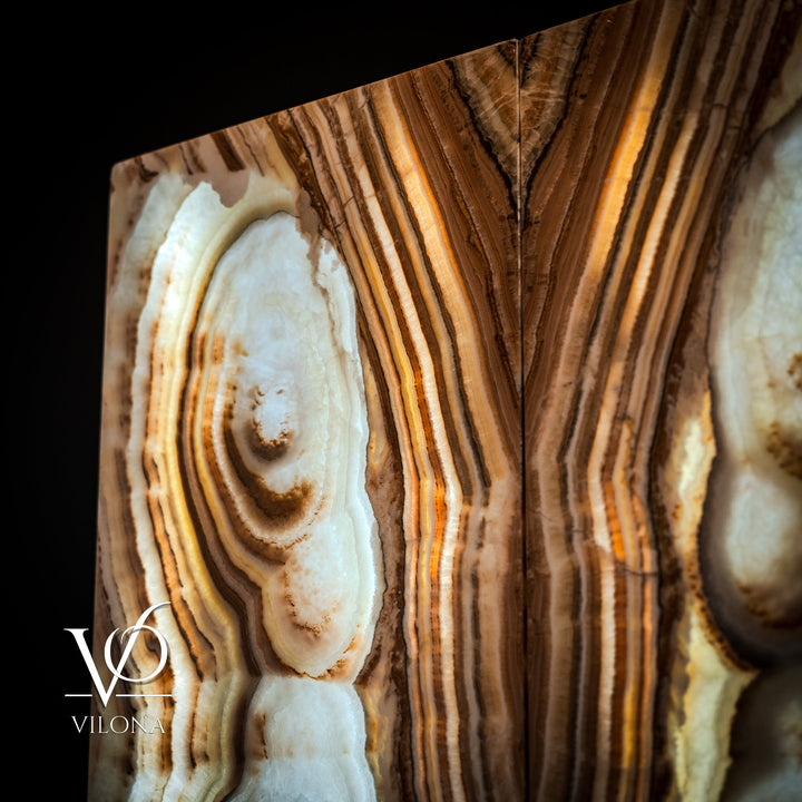 Sahara onyx wall panel close-up with cream oval geode and layered tan striations.
