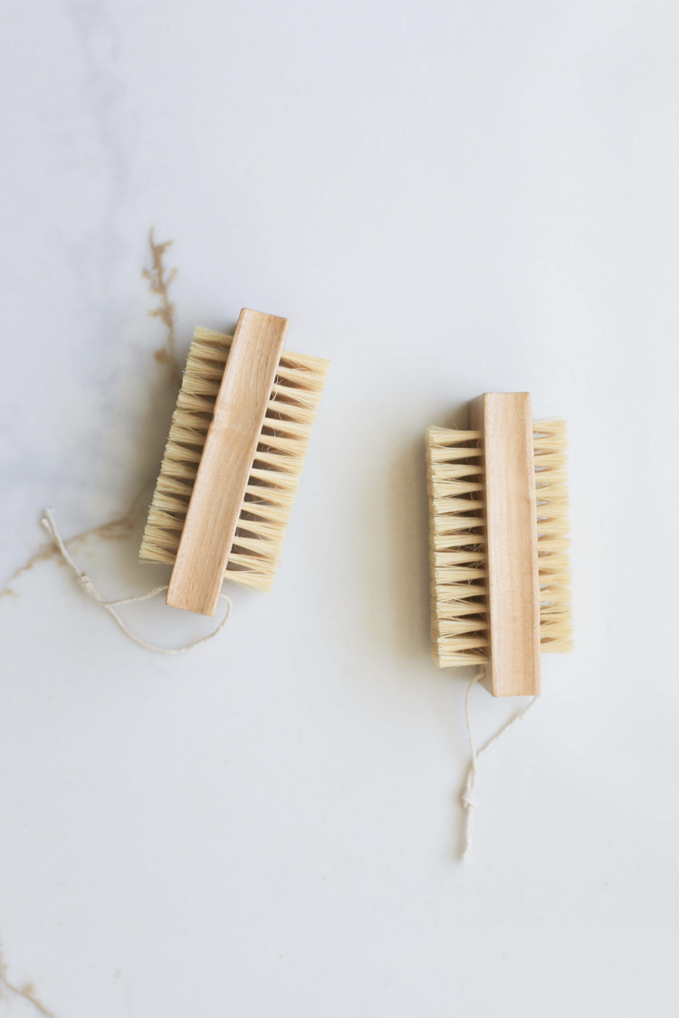 Double-sided nail brush with light wood handle and two rows of tan bristles