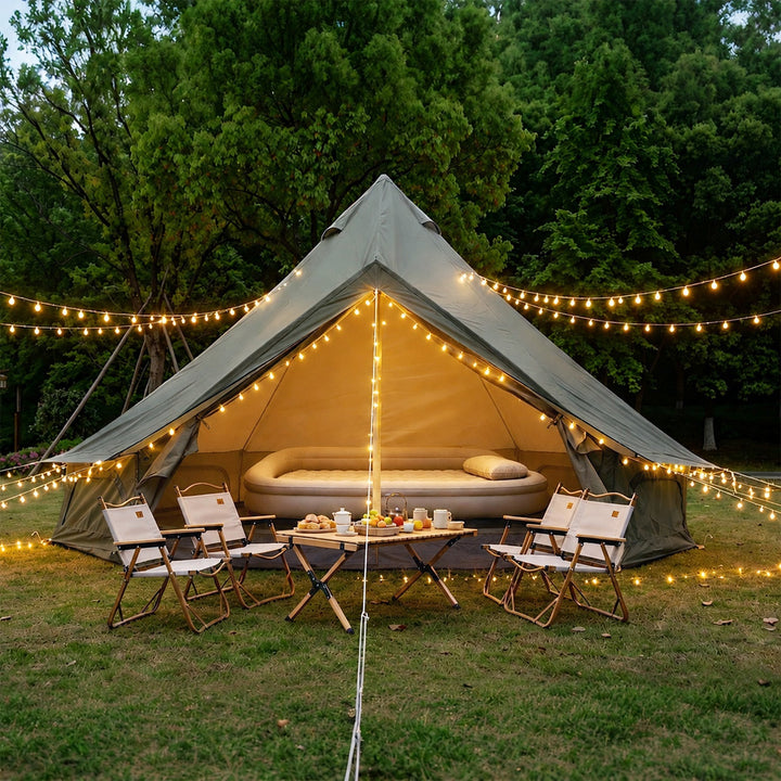 Light gray bell glamping tent with open entrance, inner canopy and warm string lights