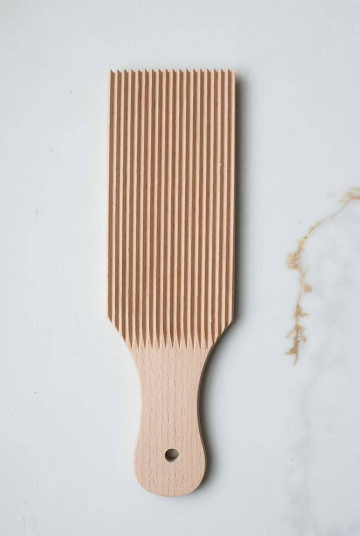 Wooden gnocchi board with vertical ridges, curved handle and small black dot