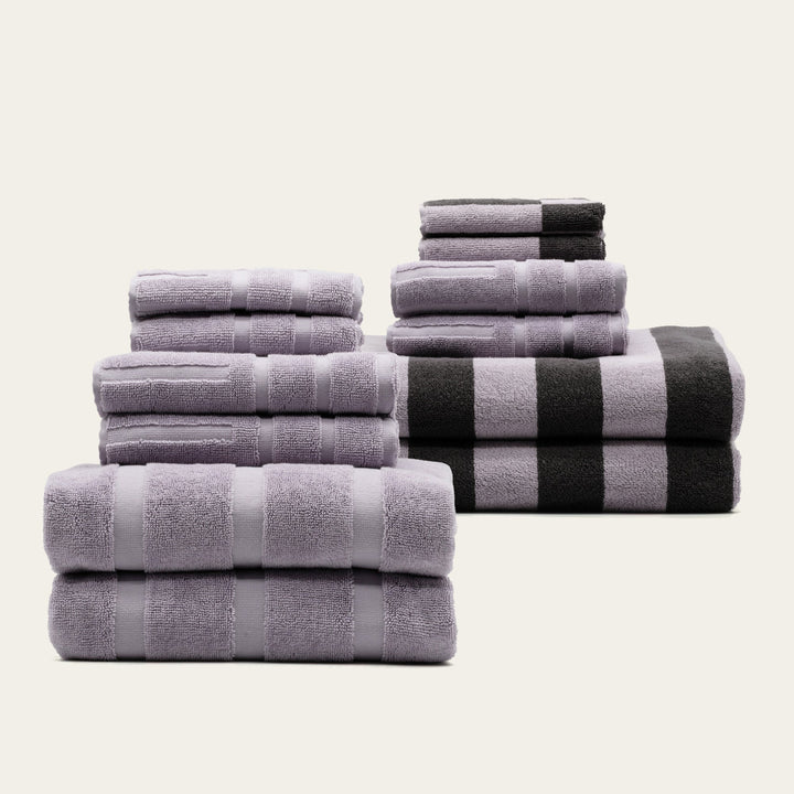 Folded lavender and gray cotton towels set, with a black-and-white striped towel.
