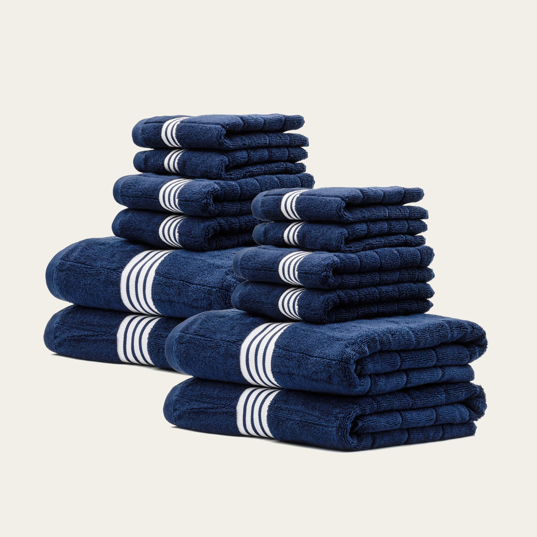 Multiple navy cotton towels stacked with white striped bands