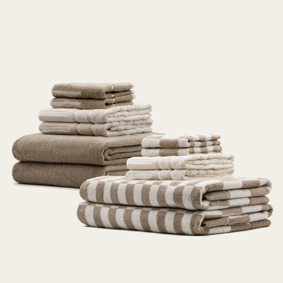 Stacked tan, ecru, and striped cotton towels, folded in different sizes