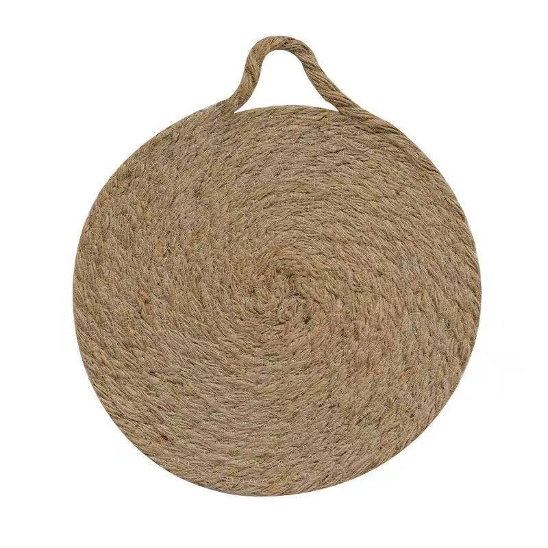 Round woven natural trivet with top handle loop, angled view