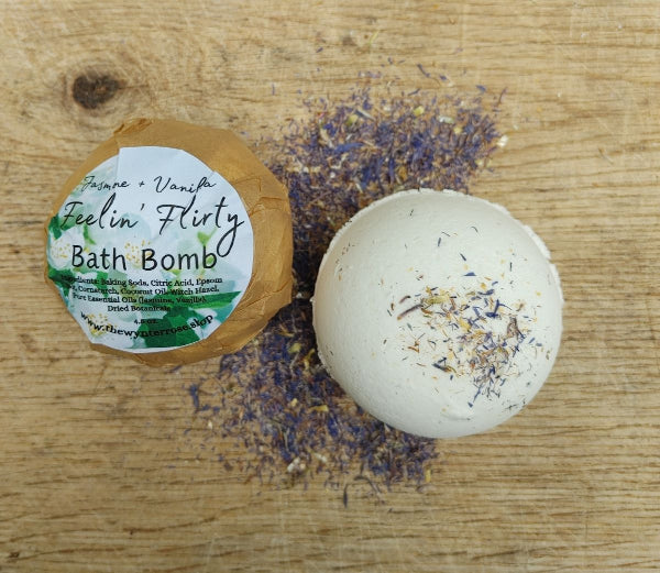 White bath bomb with blue-purple and yellow dried flower pieces on top