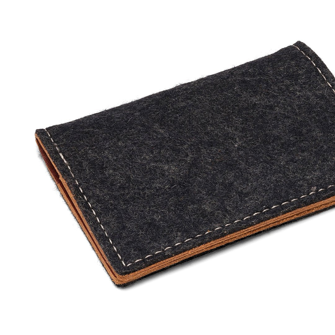 Charcoal felt bifold wallet angled view with tan leather bottom and stitched edge.