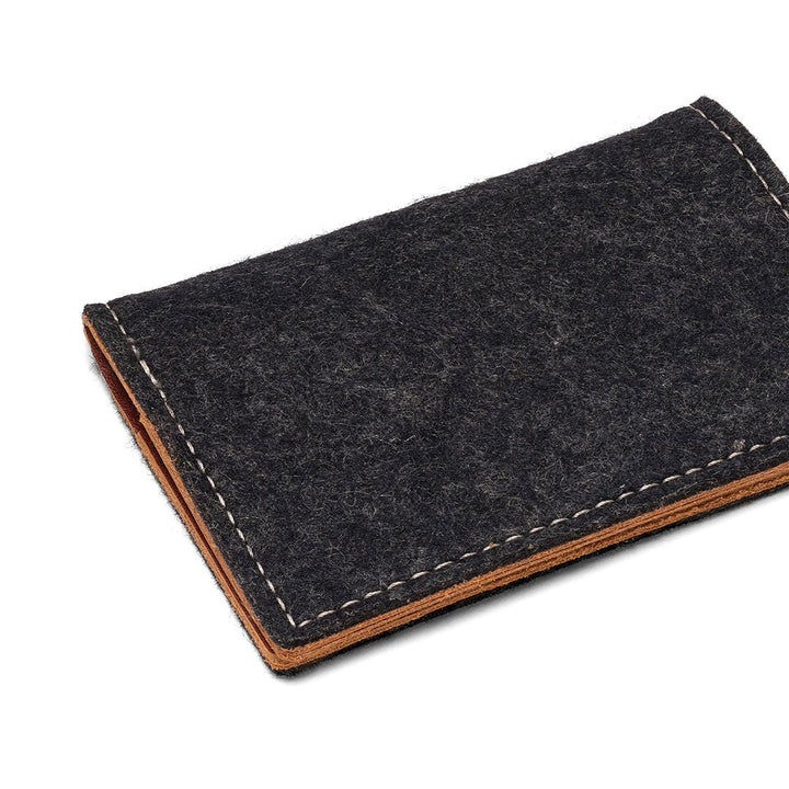 Charcoal felt bifold wallet angled view with tan leather bottom and stitched edge.