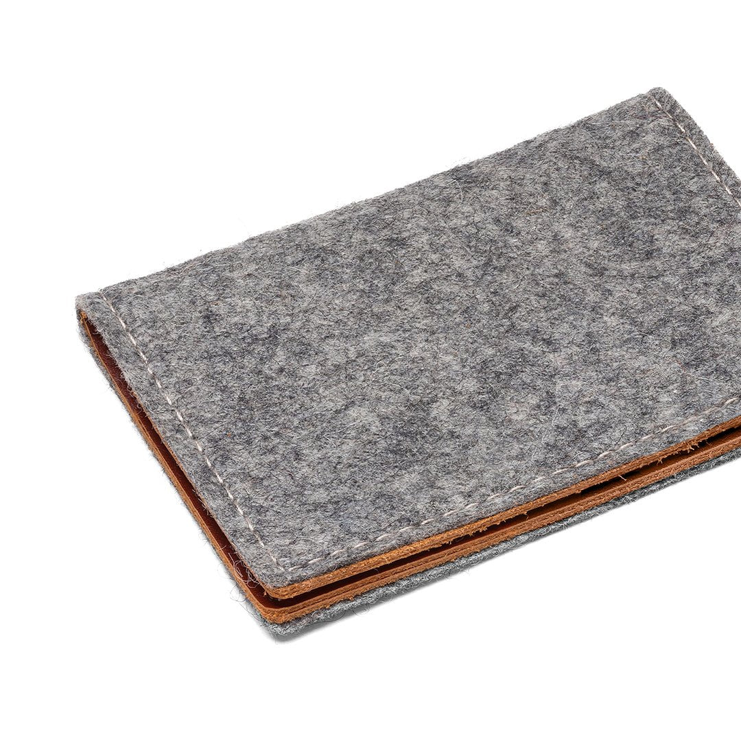 Gray felt bifold wallet angled view with tan leather bottom and stitched edge.