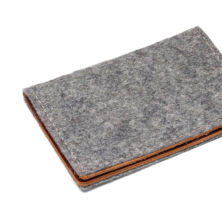 Gray felt bifold wallet angled view with tan leather bottom and stitched edge.