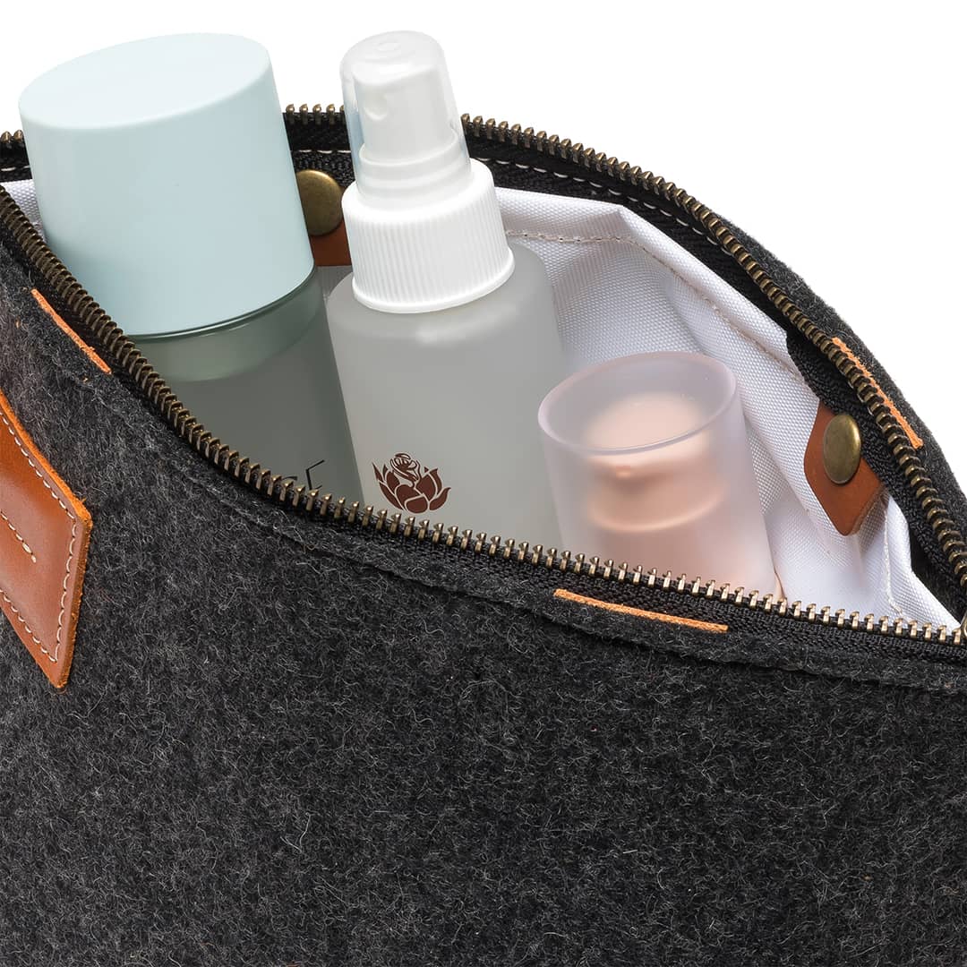 Charcoal felt travel pouch interior with bottles and gold zipper trim