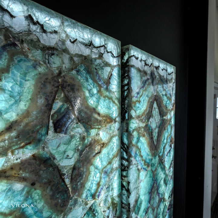 Close-up of two teal fluorite wall panels with faceted star motif and dark crack lines.