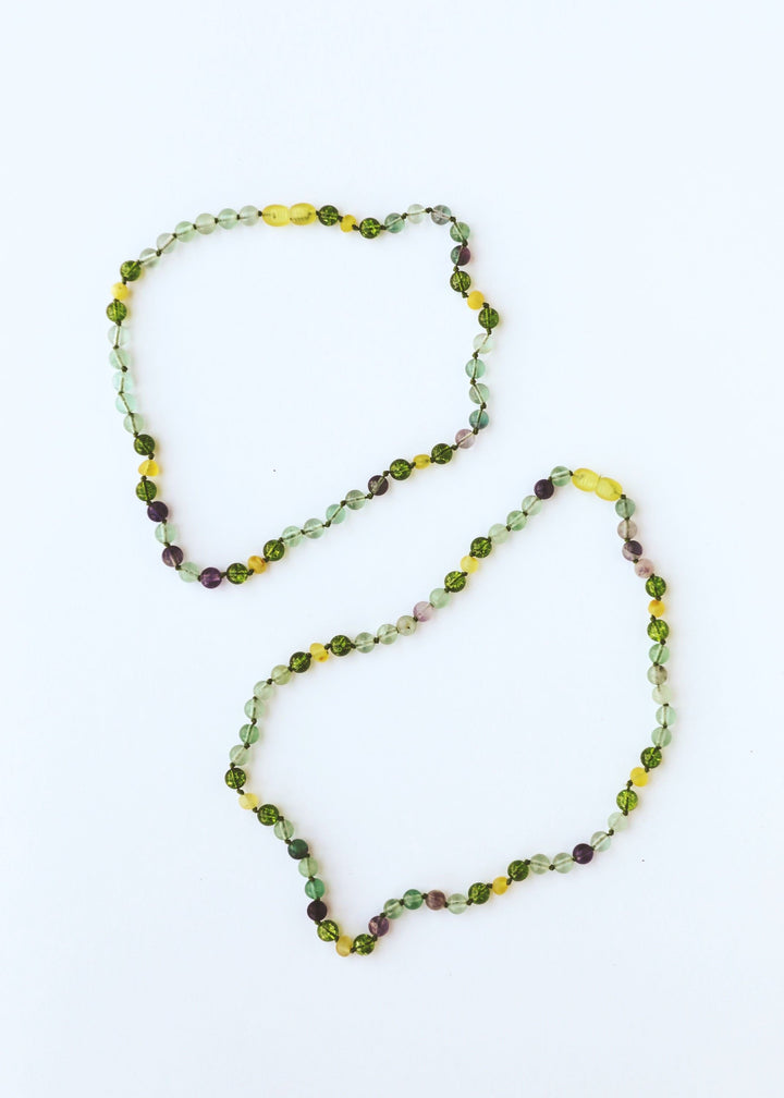 Two looping gemstone bead necklaces, green and yellow with small purple accents