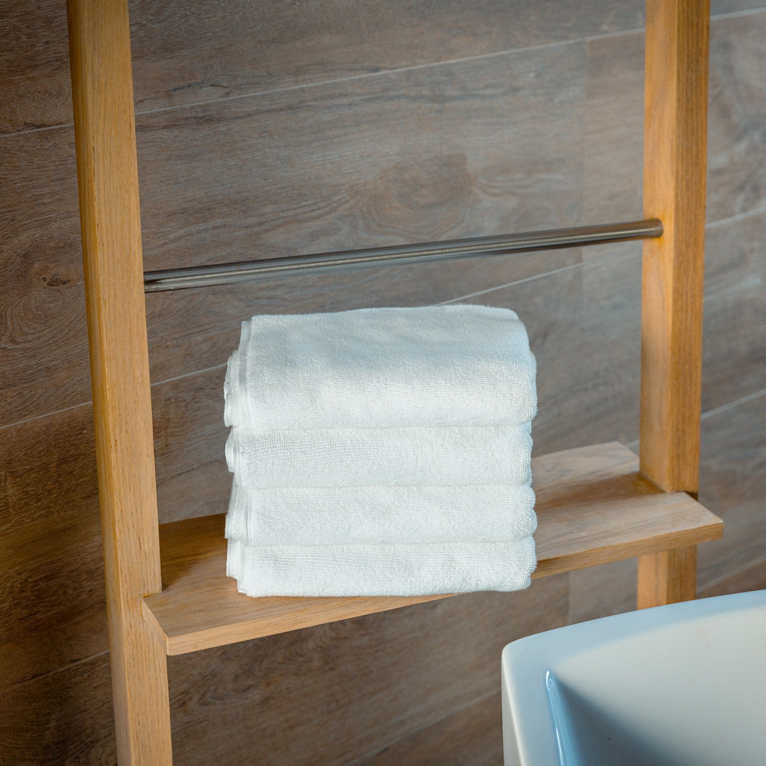 Stack of white bath mats neatly folded on a wooden chair.