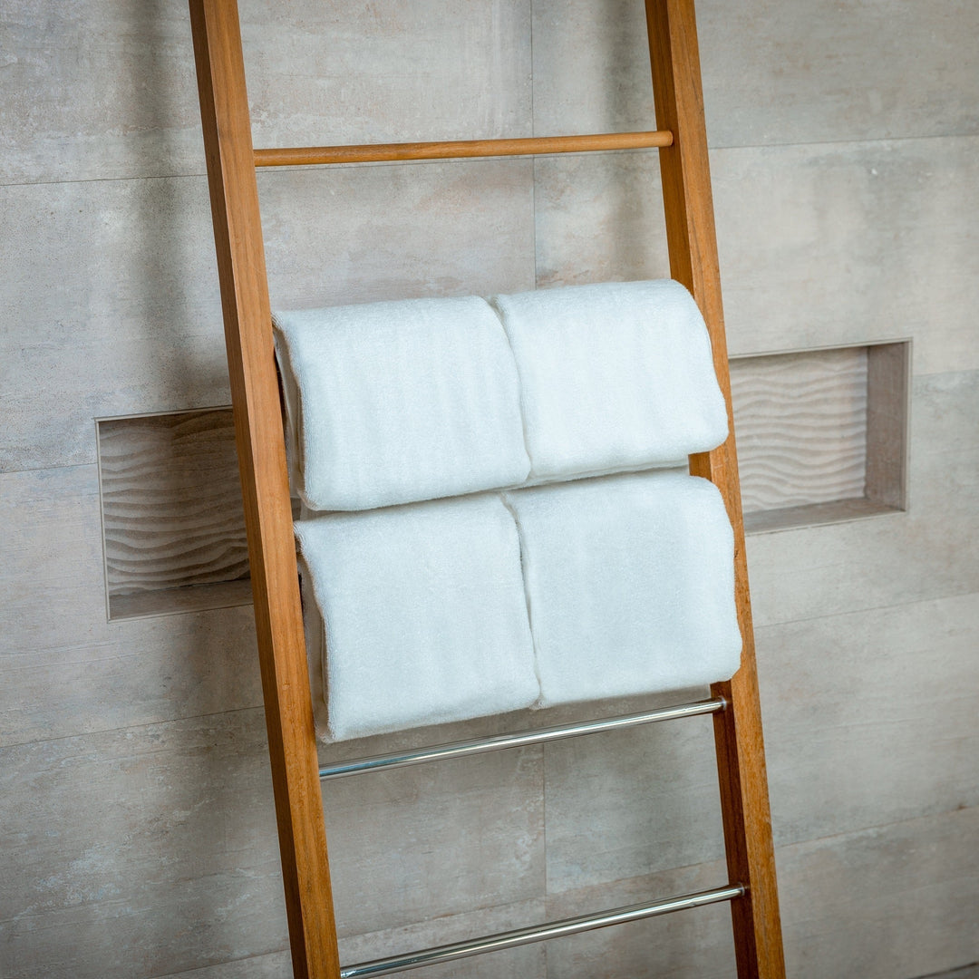 White bath towels folded in pairs on ladder towel rack