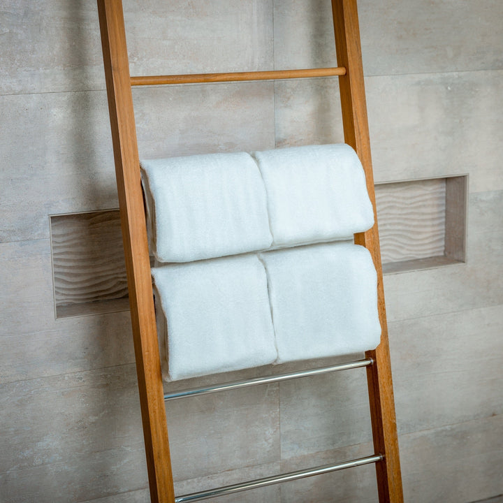 White bath towels folded in pairs on ladder towel rack