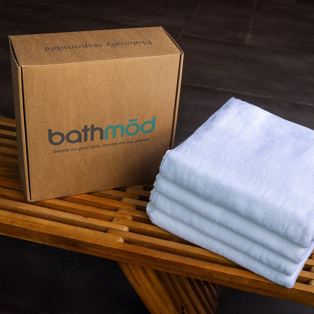 Organic bath towel four-pack, folded white towels beside a bathmod box