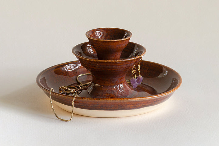 Brown ceramic jewelry fountain with gold chain and dangling earrings