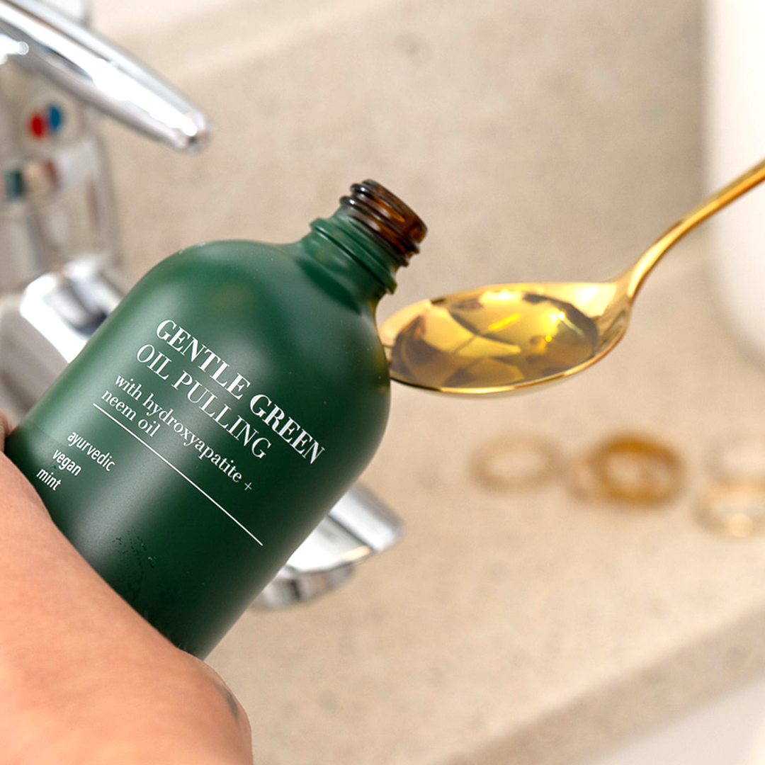 Gentle Green oil pulling oral rinse bottle with golden oil drizzled from spoon