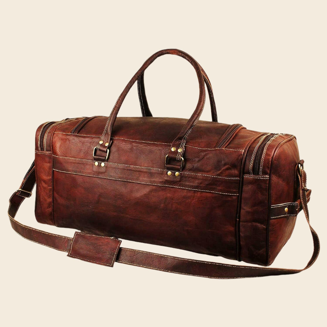 Brown leather duffel bag with top handle and end strap, front three-quarter view