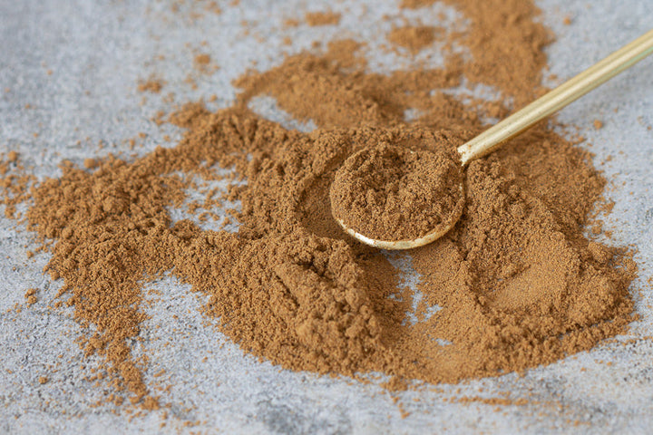 Gingerbread spice powder with spoon on light surface