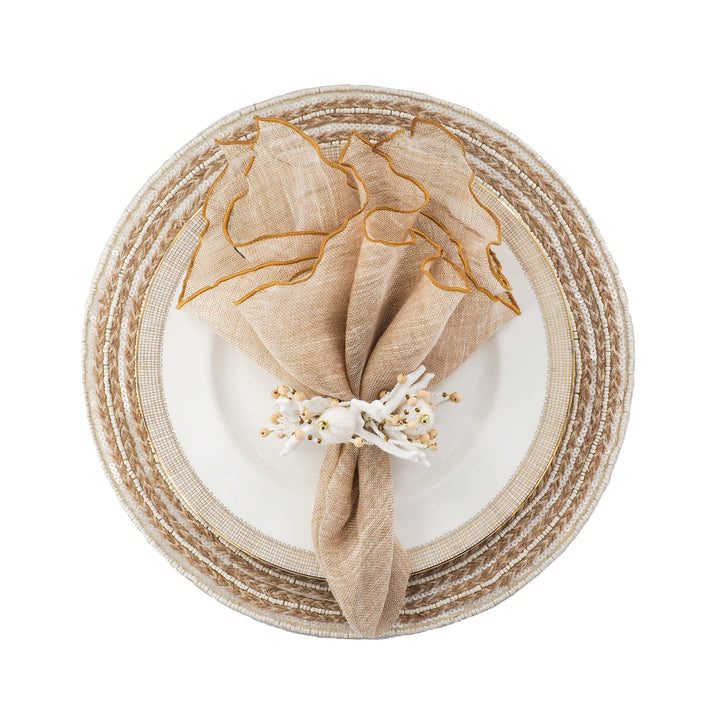 Beige linen napkin with gold ruffled edges and white floral embellishment