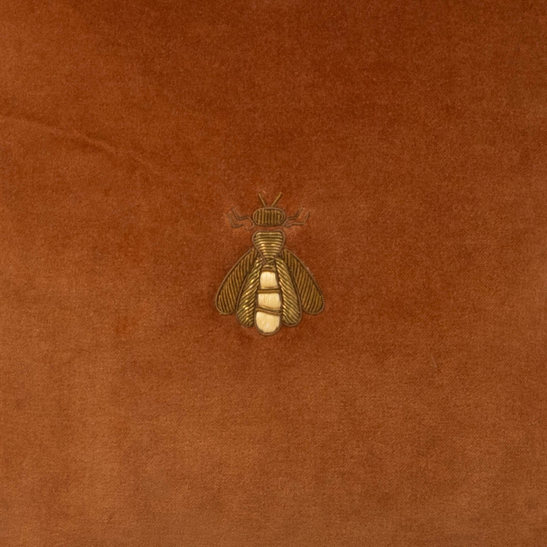 Brown velvet pillow with gold-tone embroidered bee emblem center detail