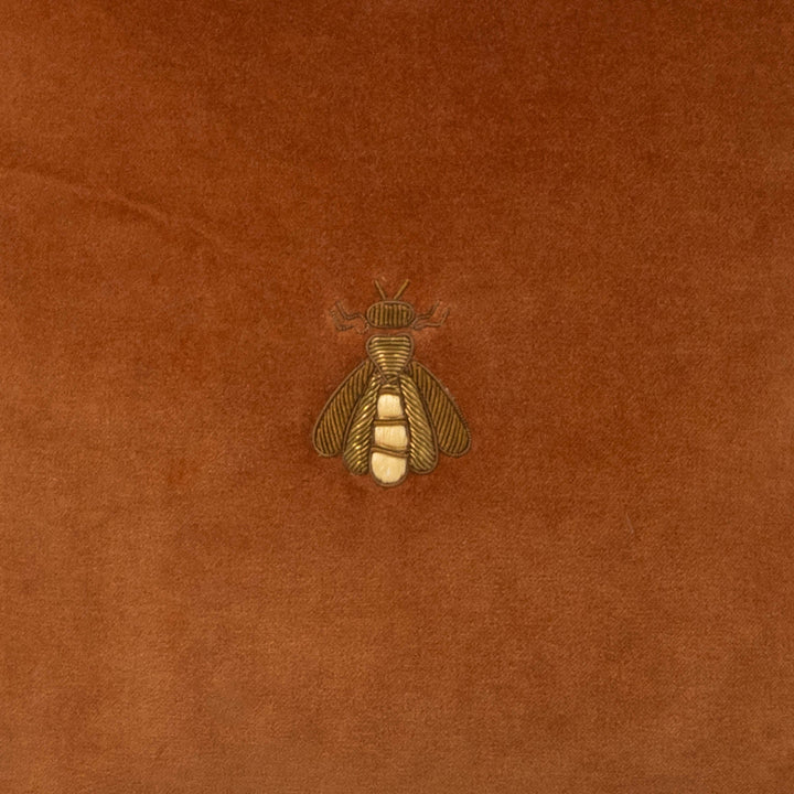 Brown velvet pillow with gold-tone embroidered bee emblem center detail