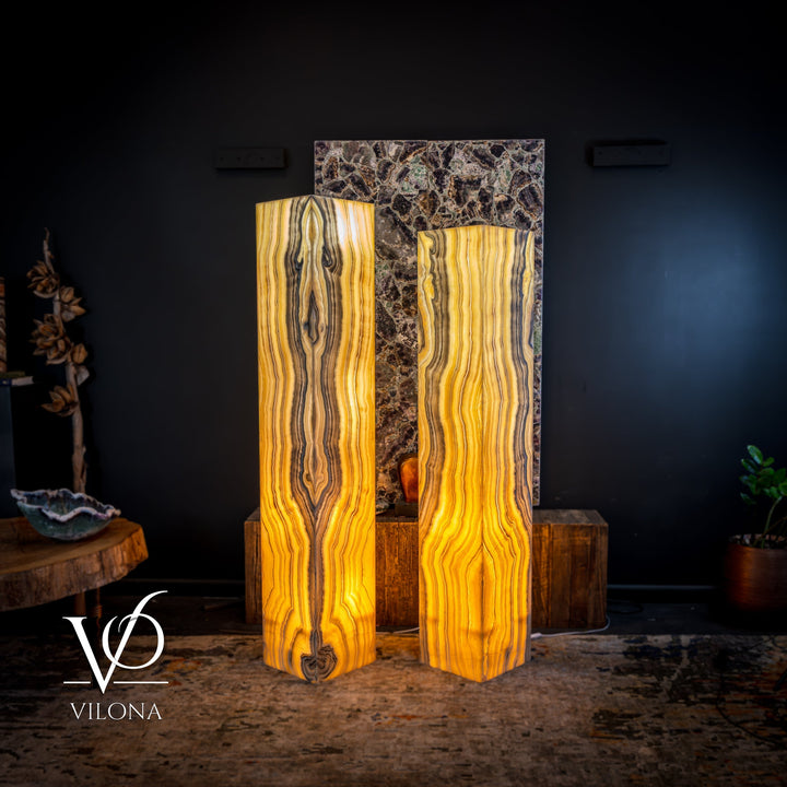 Pair of tall onyx floor lamps showing glowing amber light through striped shades