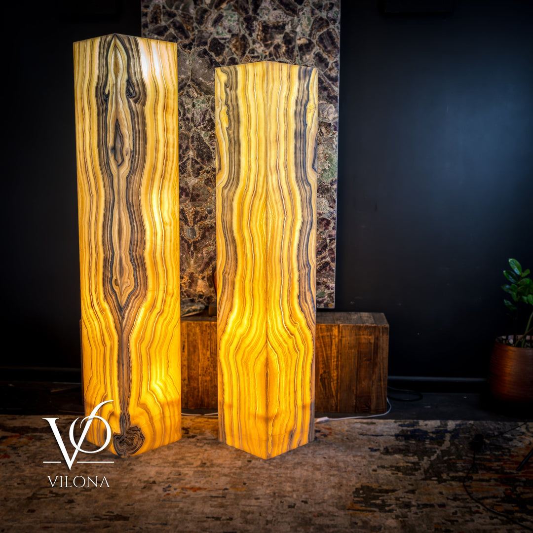 Pair of large onyx floor lamps with glowing amber light and vertical wave-like veining
