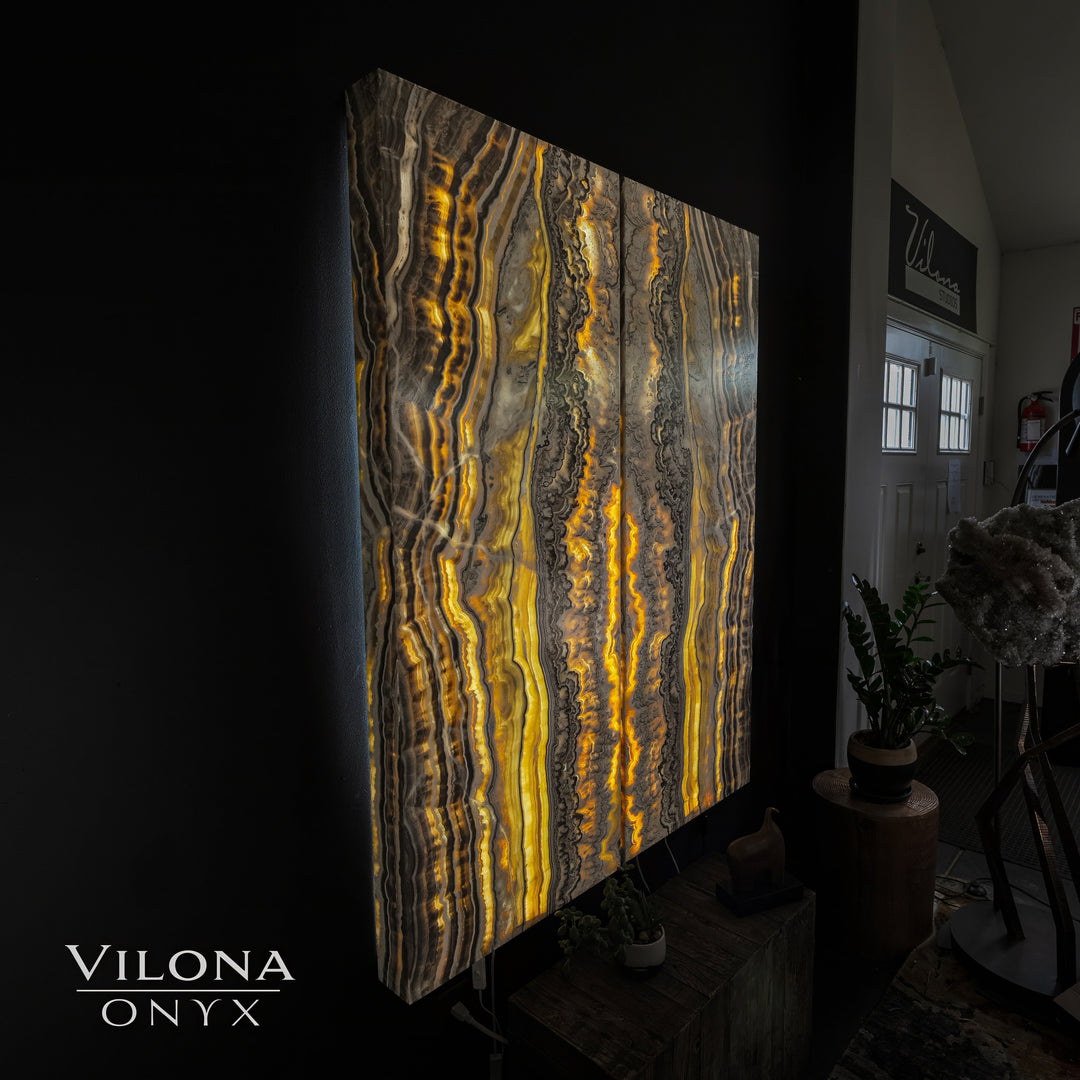 Onyx wall panel leaning indoors with vertical amber-gold and gray stone veining.